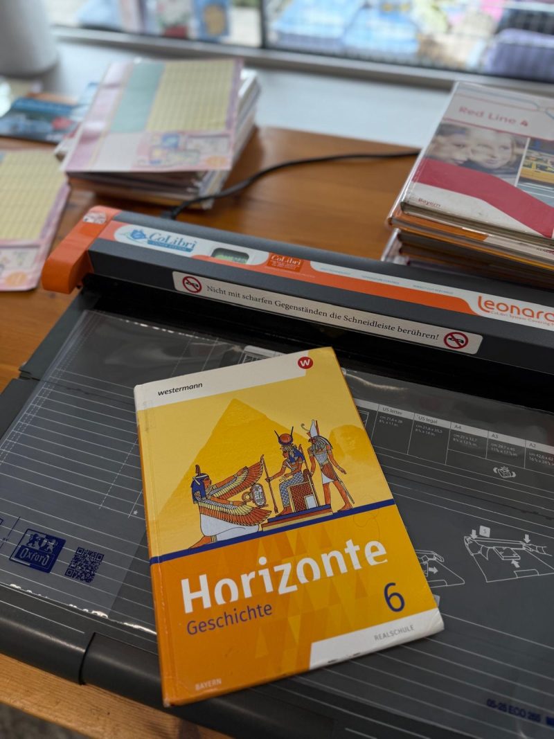 Ein Schulbuch liegt zum Einbinden auf dem CoLibrì-System im Ladengeschäft.